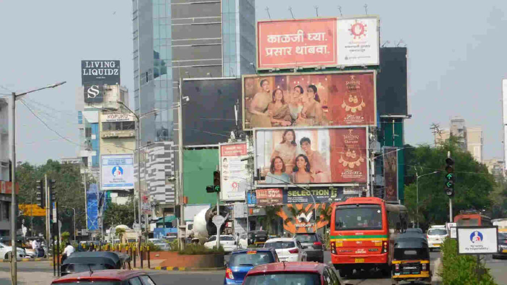This image depicts several advertisements on the billboard on a road and people on the move