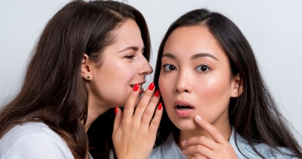 Two young girls talking to each other, possibly discussing word-of-mouth marketing.