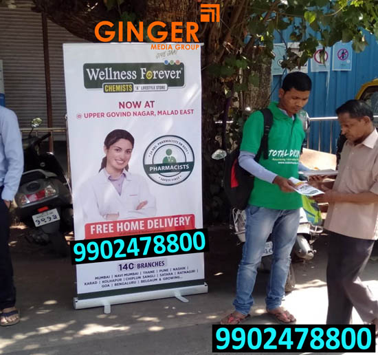 A boy is distributing Pamphltes beside a standee