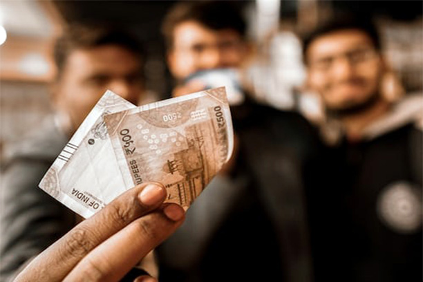 A person handing a 500 rupee note.