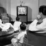 a family sitting together and watching advertisement in TV