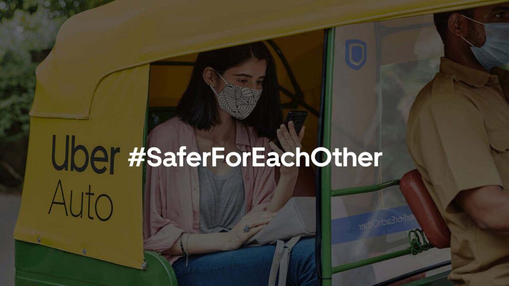 A masked passenger sitting at the back of an Uber auto and a separator separating the driver and the passenger.